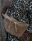 woman wearing a leopard print coat with a  dark taupe suede large crossbody handbag. 