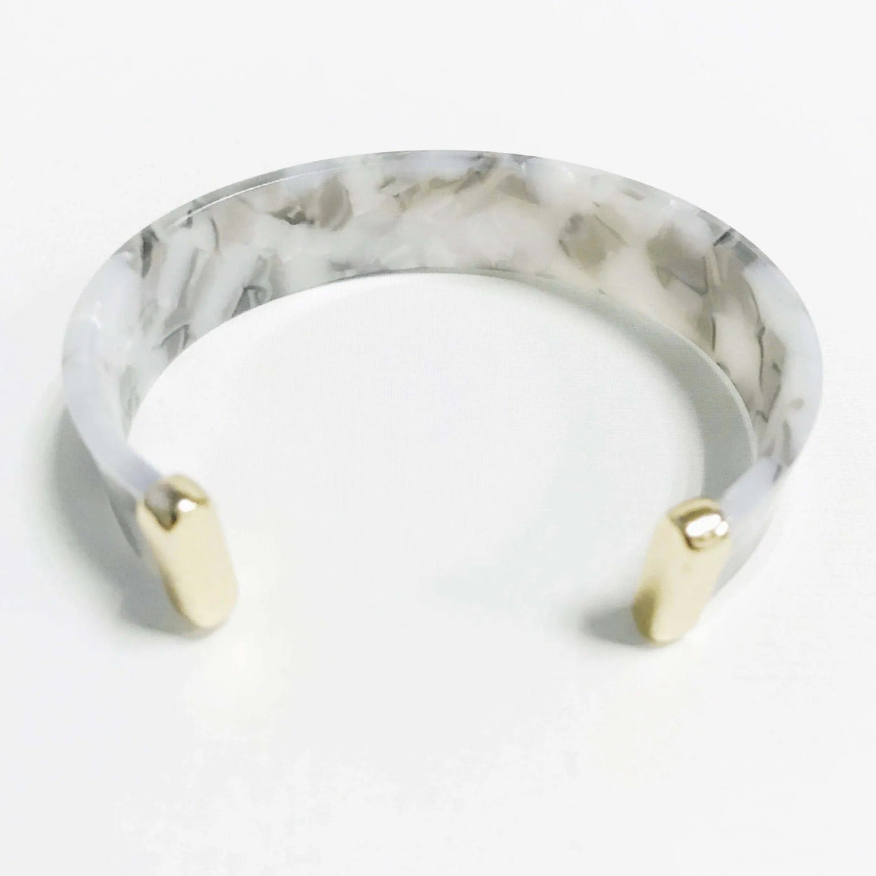 grey Marble-patterned cuff bracelet with gold accents on a white background