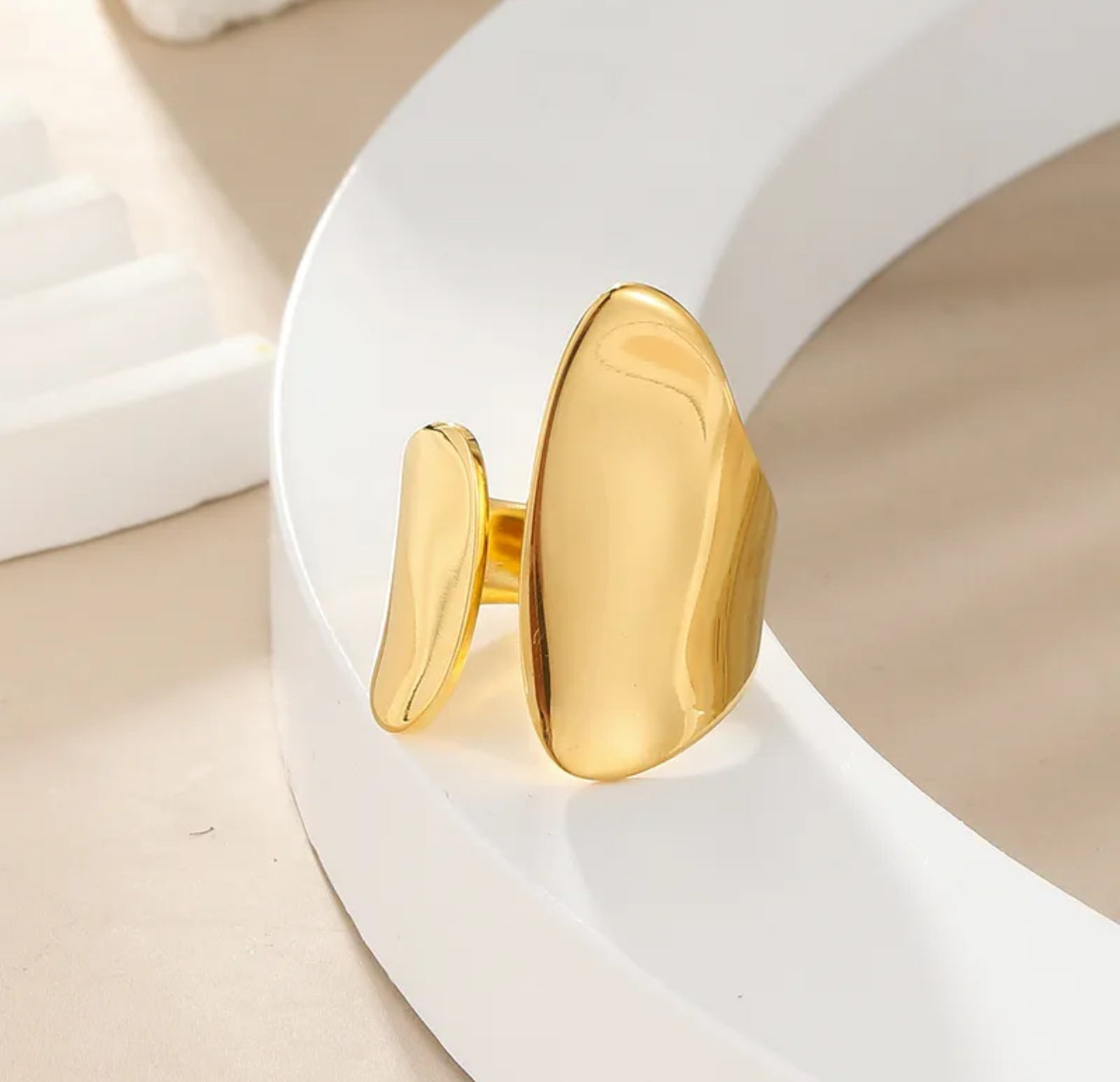 Gold chunky adjustable ring on a white plate 