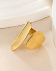 Gold chunky adjustable ring on a beige surface with a white background