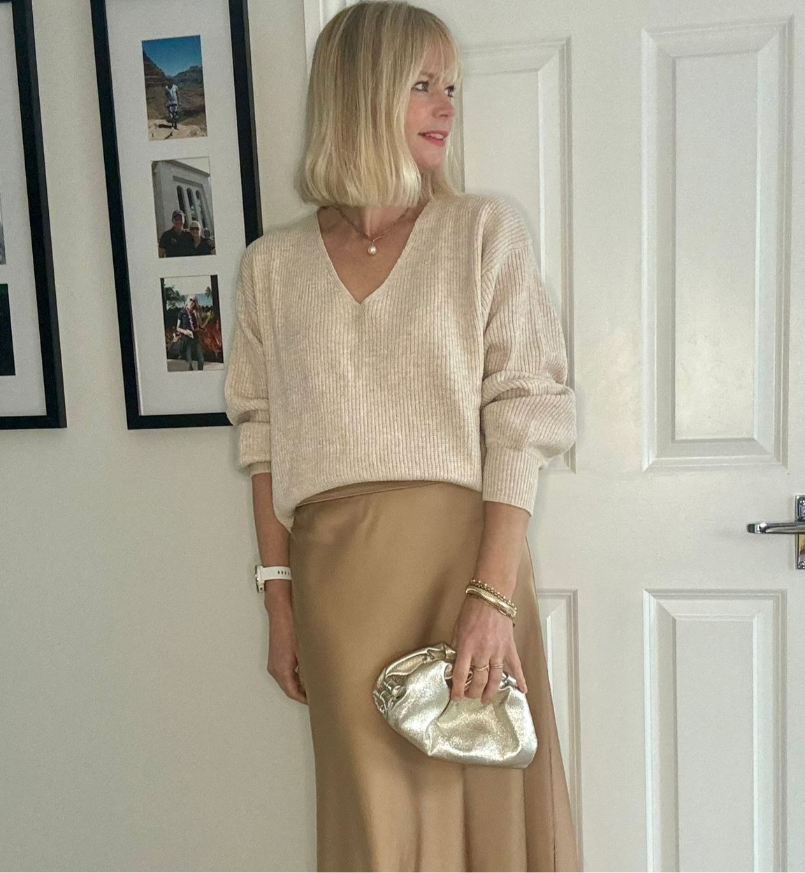 A person holding a gold clutch bag with a cloud-like texture, likely made from leather, with a hinge opening. 