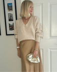 A person holding a gold clutch bag with a cloud-like texture, likely made from leather, with a hinge opening. 