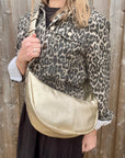 Woman wearing a leopard print jacket holding a gold crossbody handbag. 
