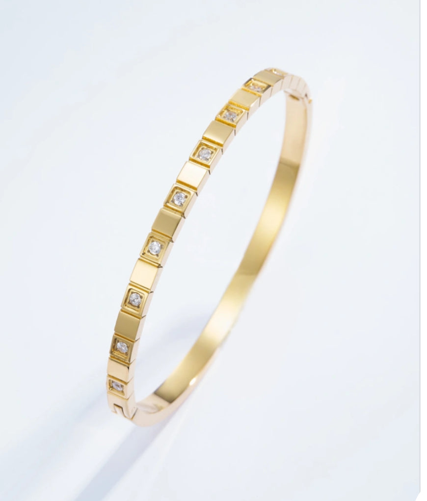 Gold bracelet with embedded diamonds on a light gray background