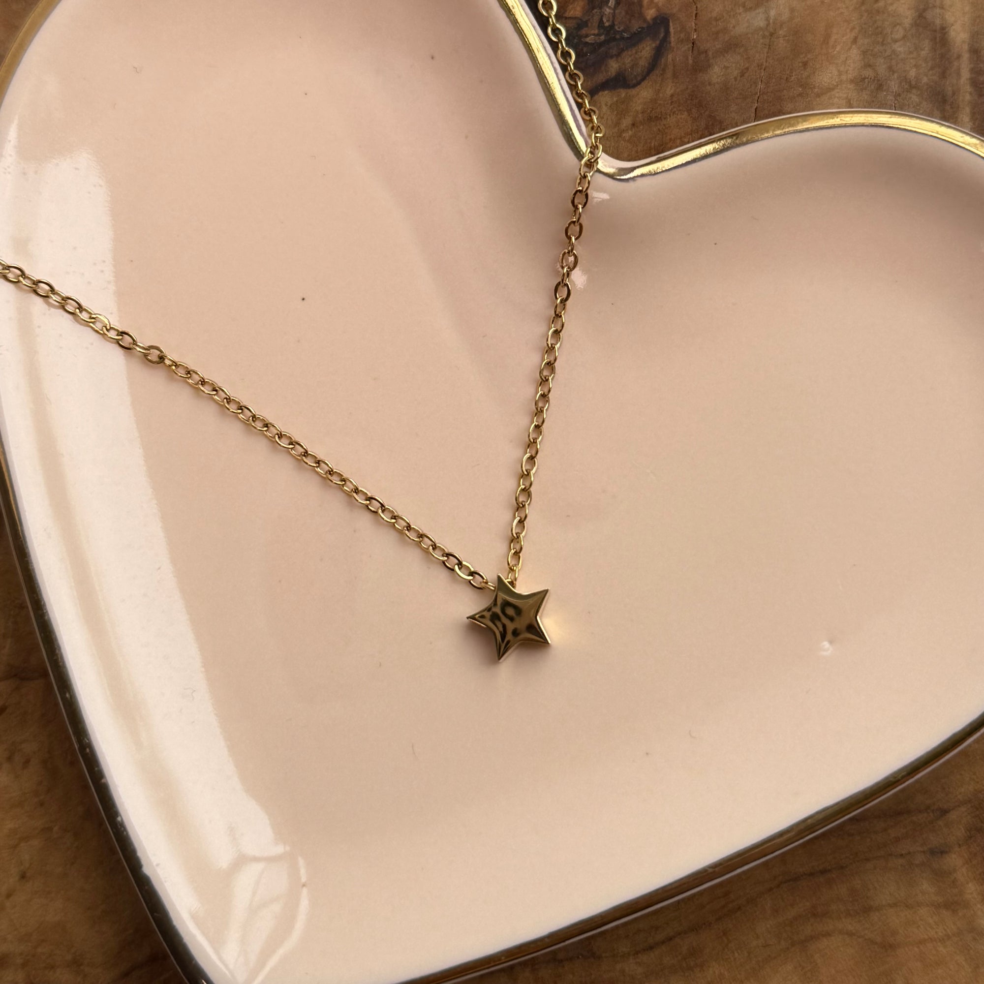 Gold necklace with a star pendant on a heart-shaped dish