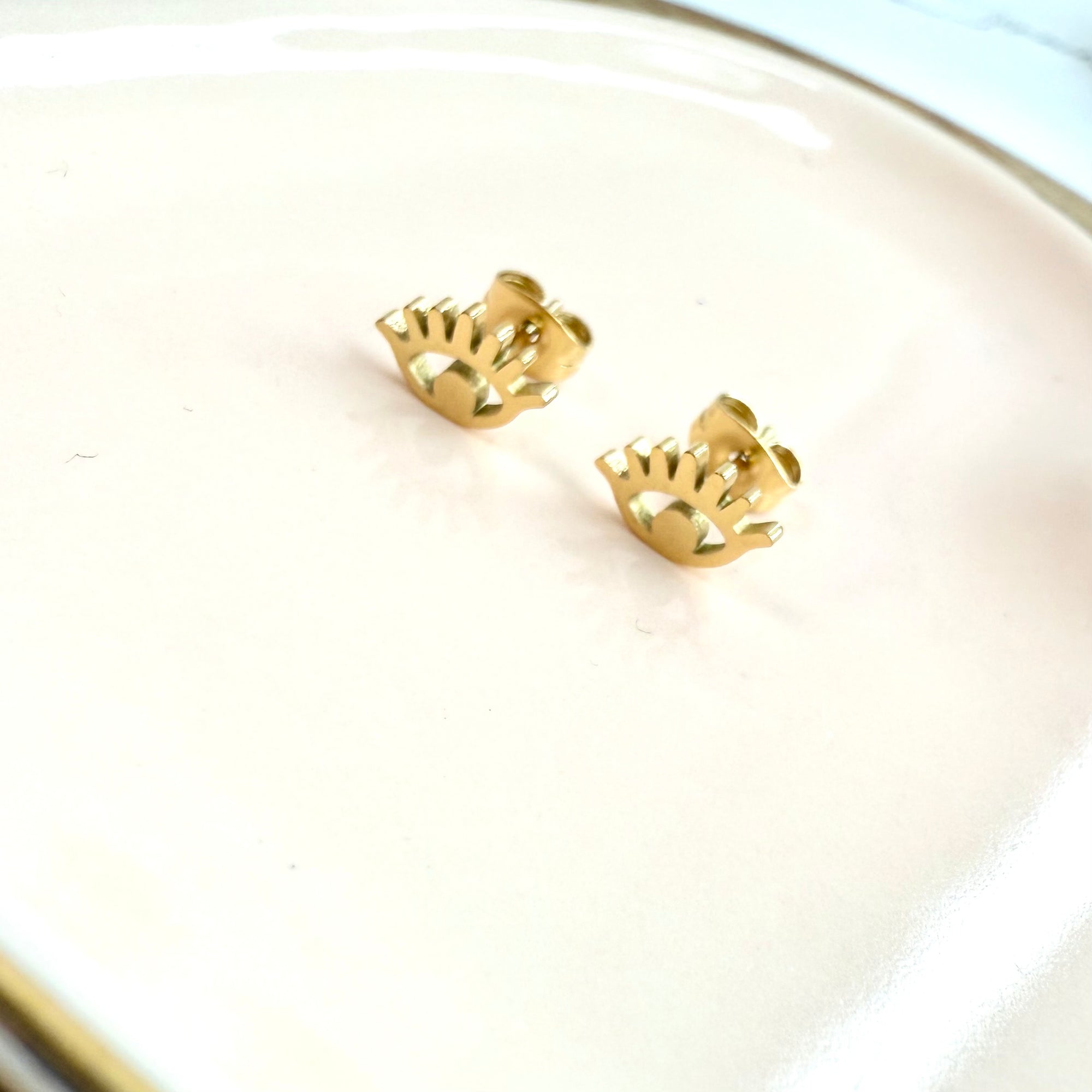 Gold evil eye earrings on a white surface