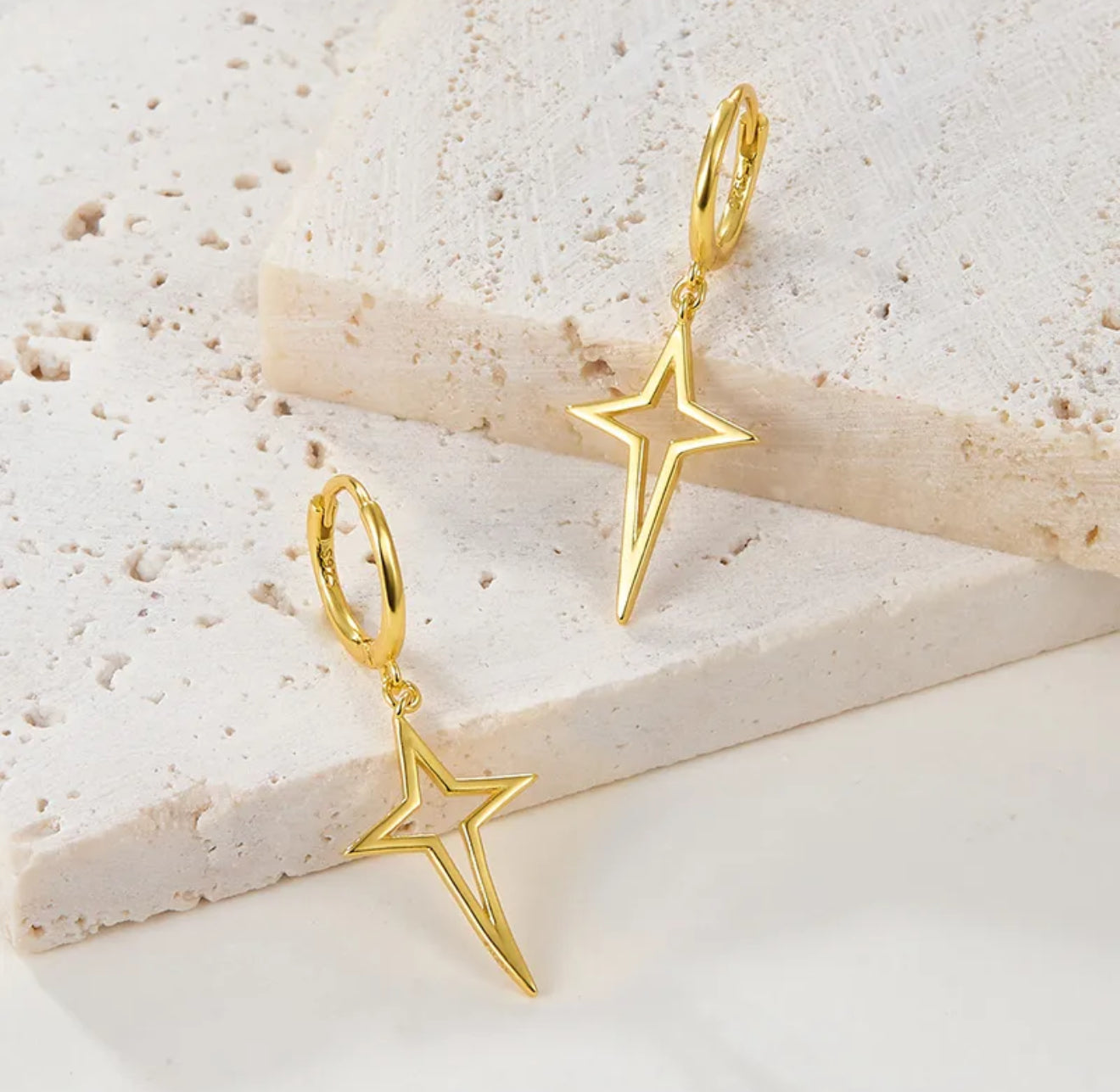 Gold star-shaped earrings on a light background