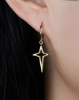 Gold star-shaped earring worn on an ear 
