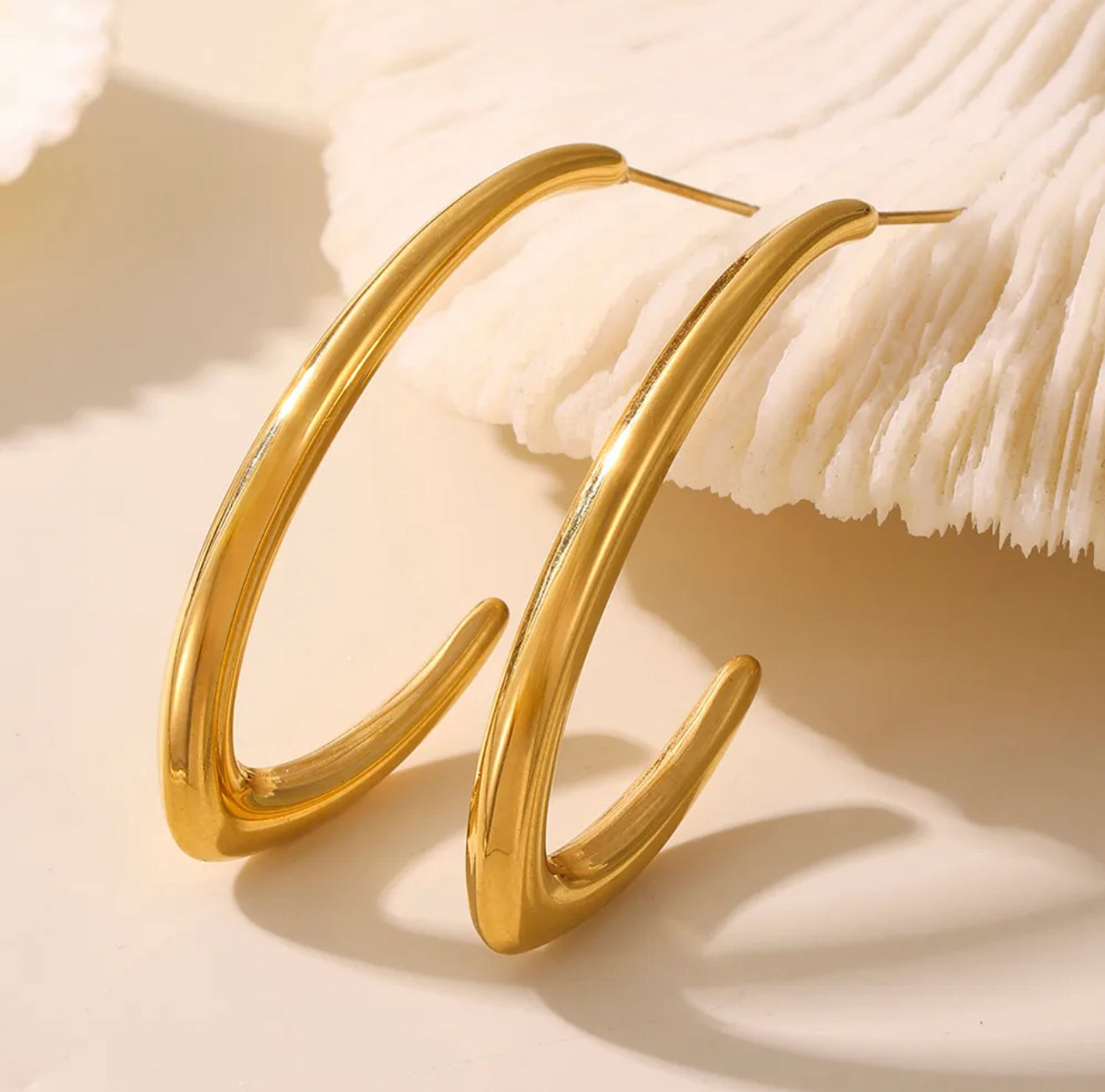 Gold hoop loop drop  earrings on a beige background