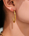 close up of gold hoop earring worn by a woman. 