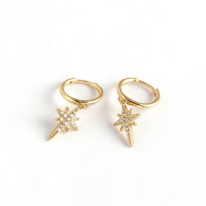 A pair of gold-colored hoop huggies with star charms on a white background.