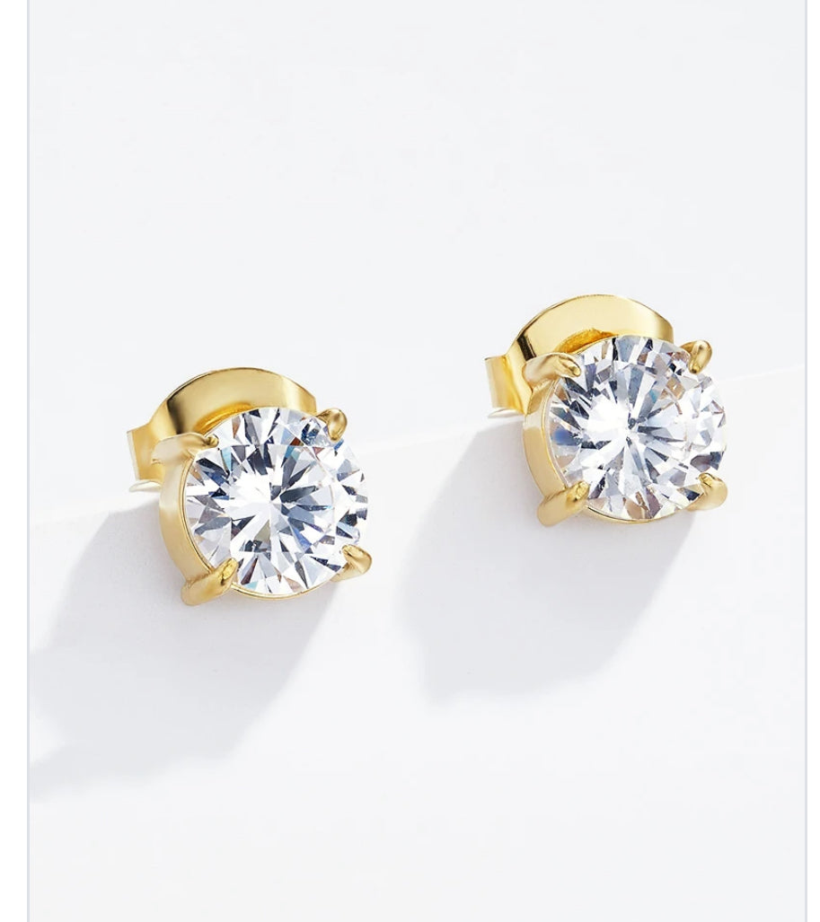 Gold earrings with large clear gemstones on a white background