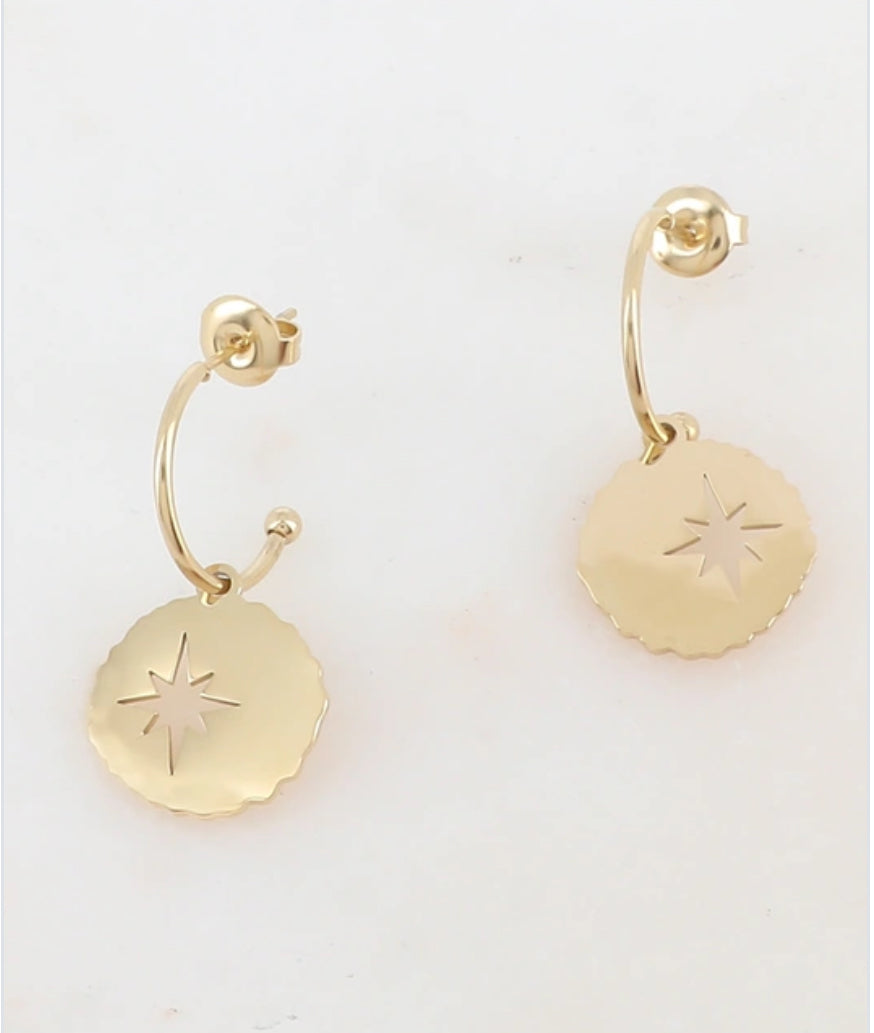 Gold hoop earrings with star designs on a light background