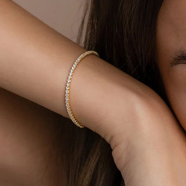 A close-up of a woman wearing a gold tennis bracelet with cubic zirconia crystals 