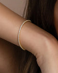 A close-up of a woman wearing a gold tennis bracelet with cubic zirconia crystals 