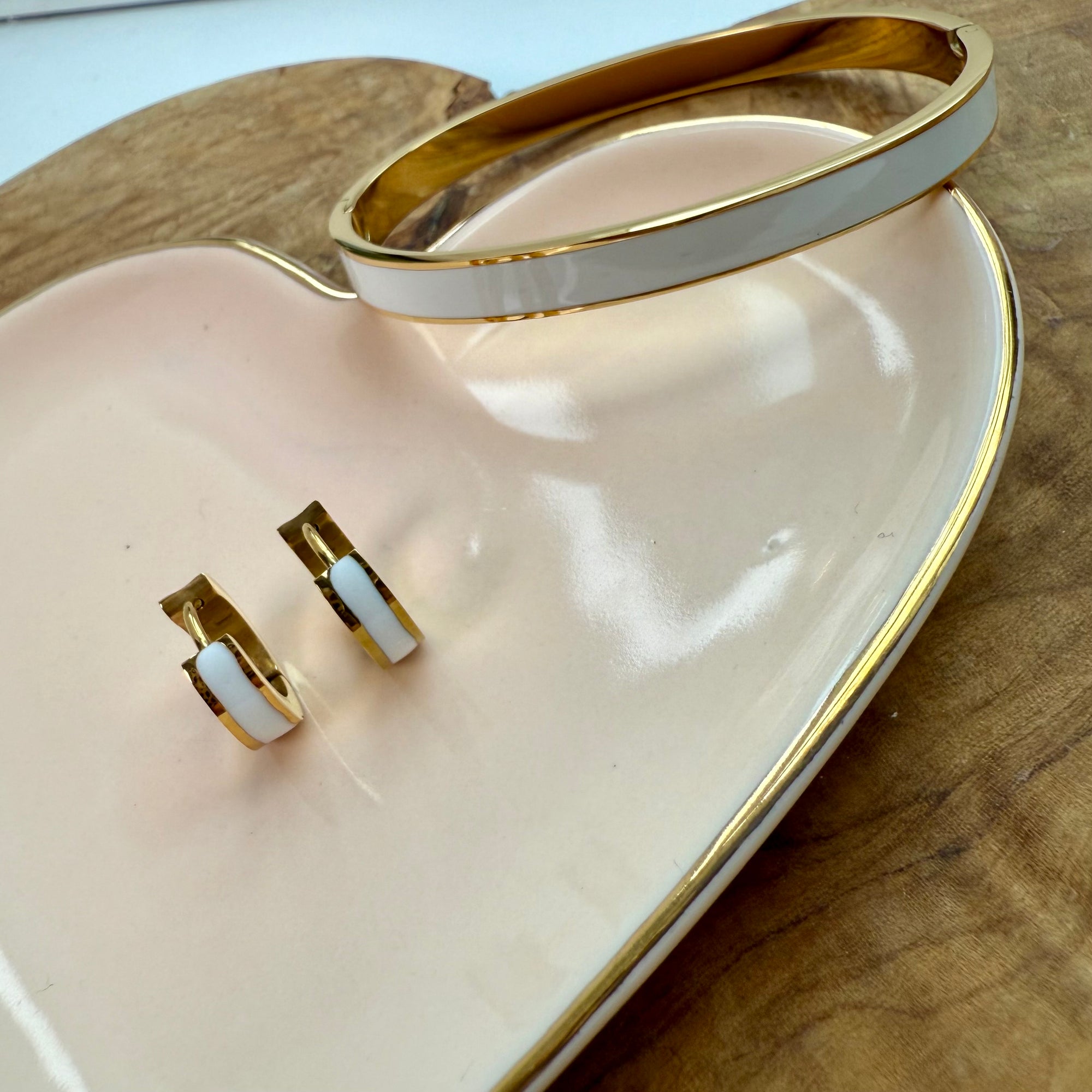 Gold and white earrings on a heart-shaped pink dish 