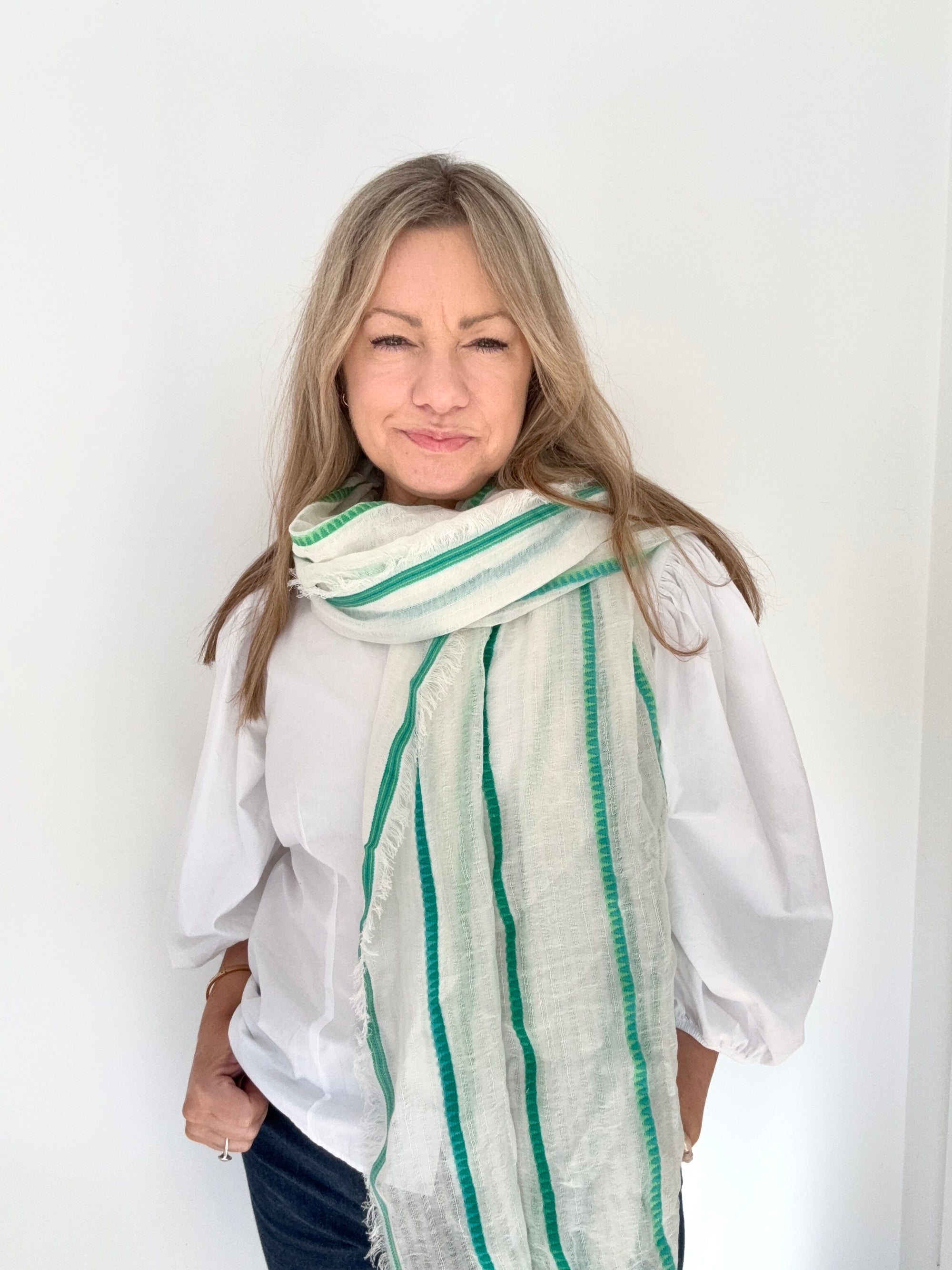 Woman wearing a white blouse and green striped scarf.