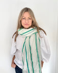 Woman wearing a white blouse and green striped scarf.