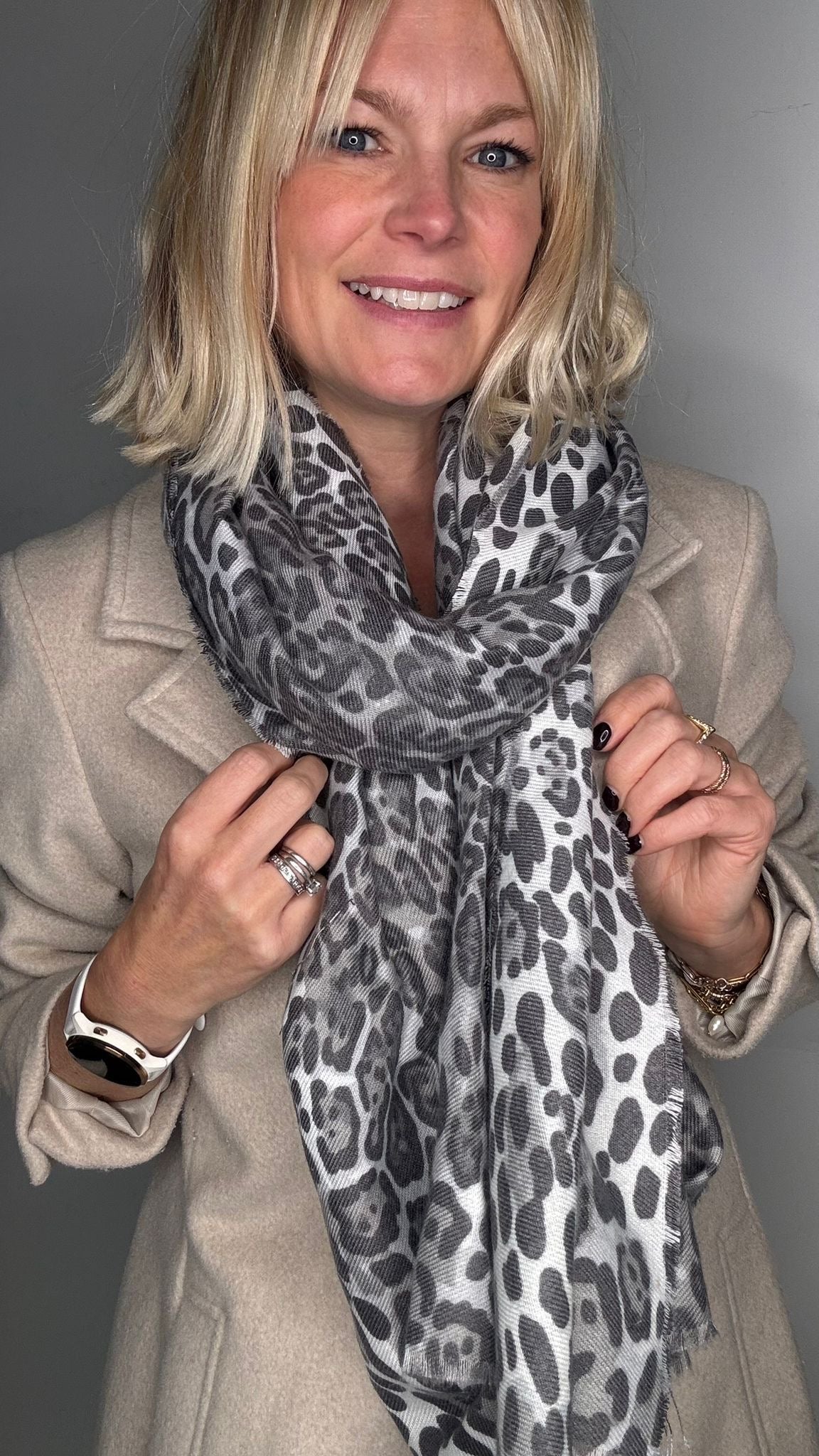 Woman wearing an animal print scarf and beige coat 