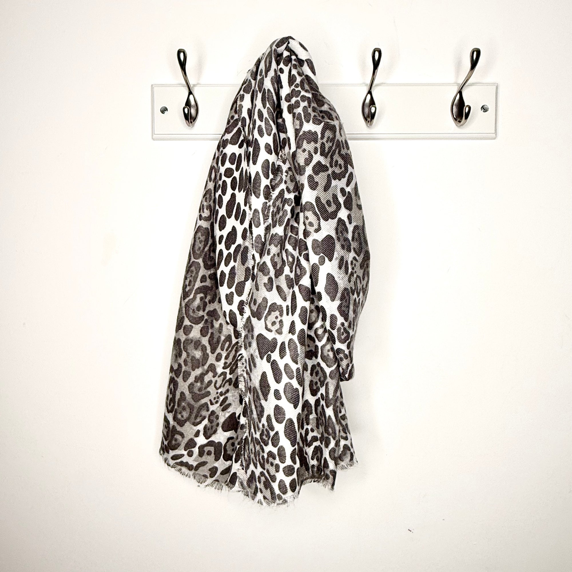 Leopard print scarf hanging on a hook on a white wall 