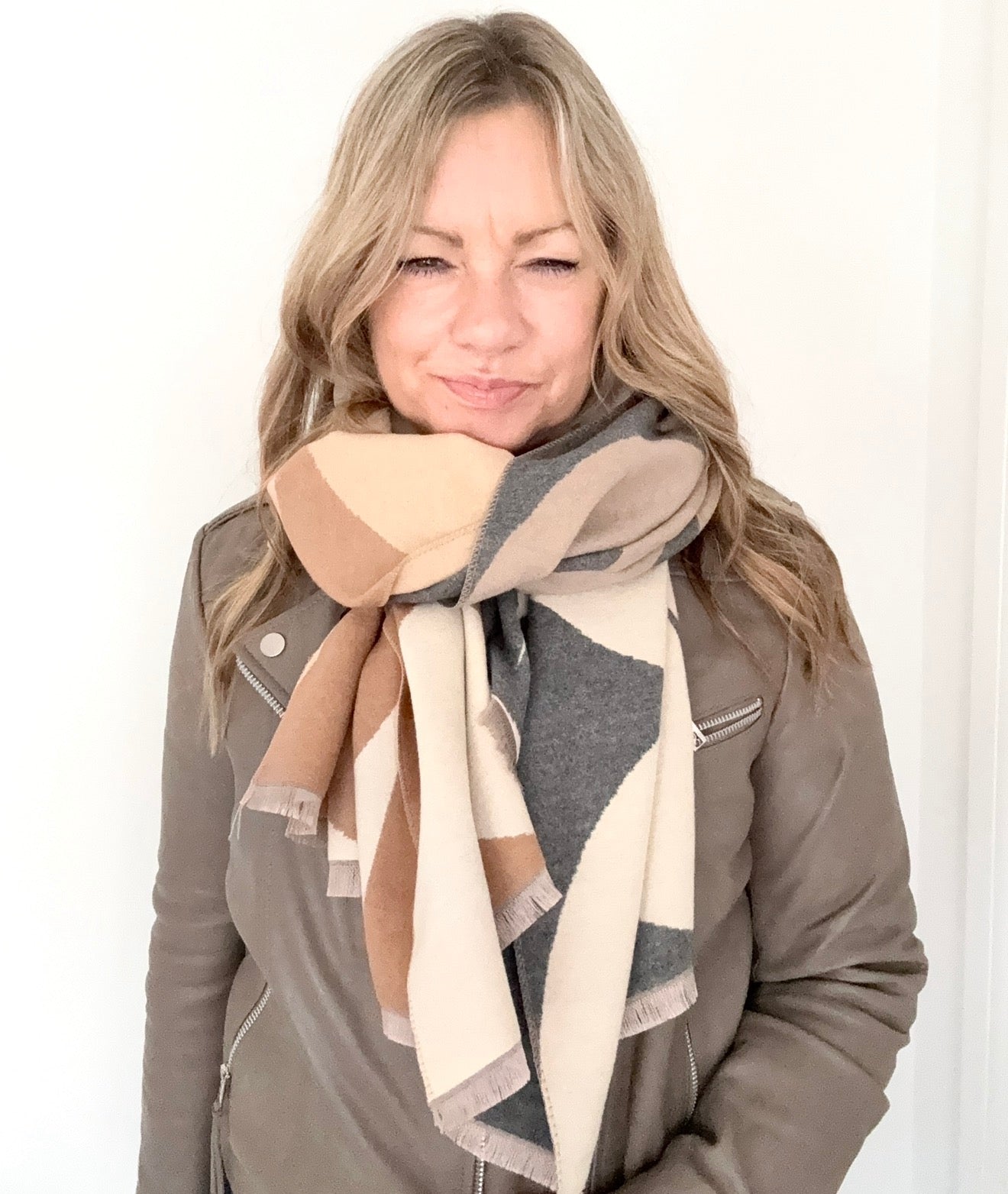 woman wearing a grey and camel retro print scarf and a suede leather jacket 