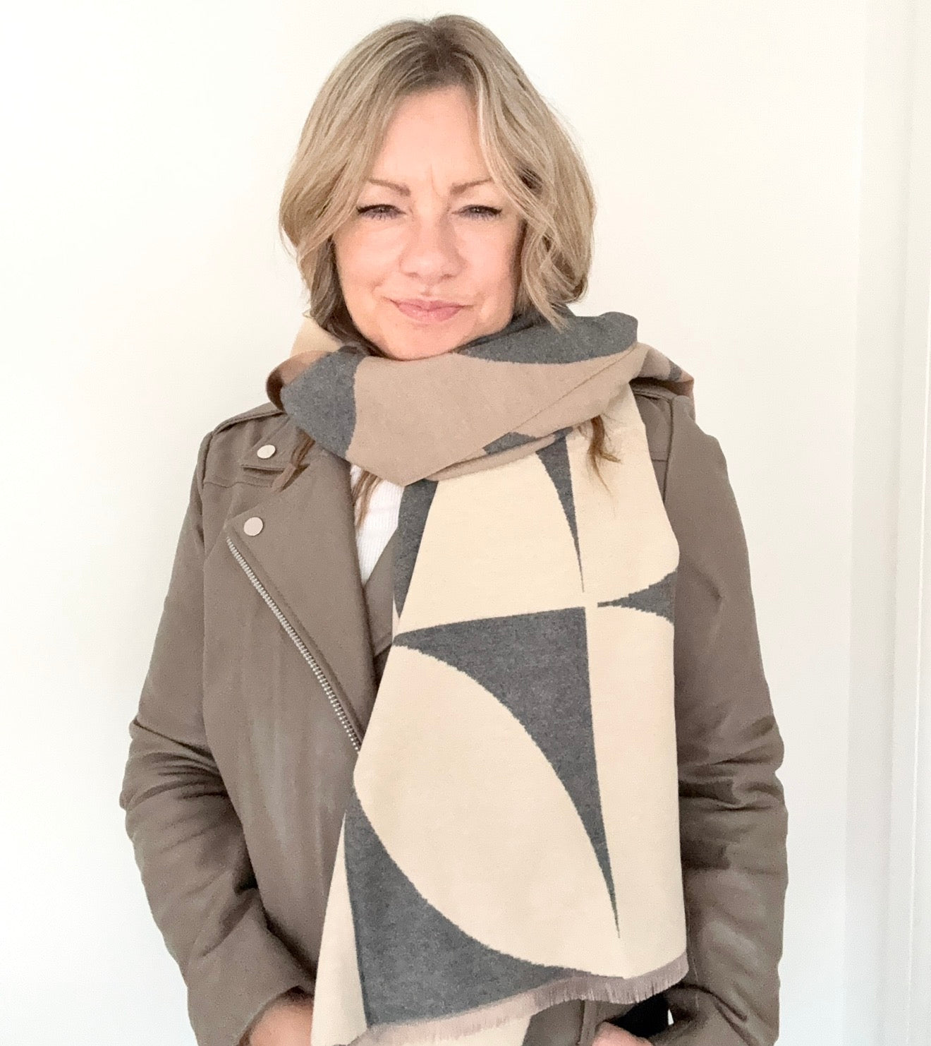 woman wearing a grey and camel retro print scarf with a suede leather jacket 