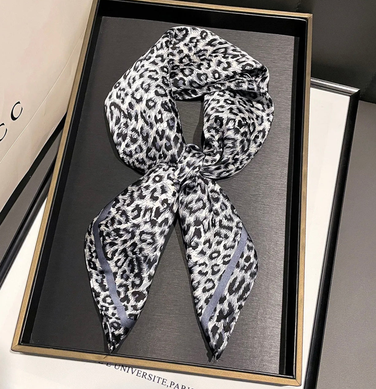 Grey mix animal print scarf in a black frame on a grey surface