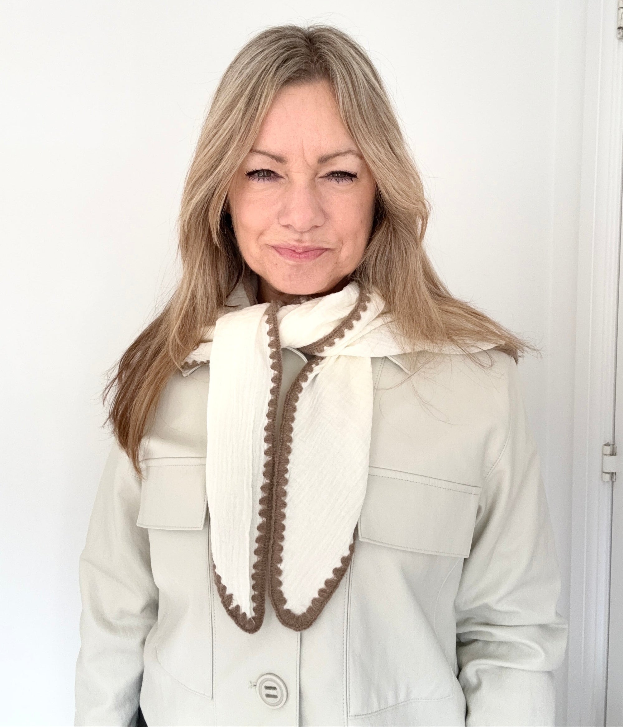 Woman wearing a light-colored coat with a cream & taupe cotton triangle scarf 
