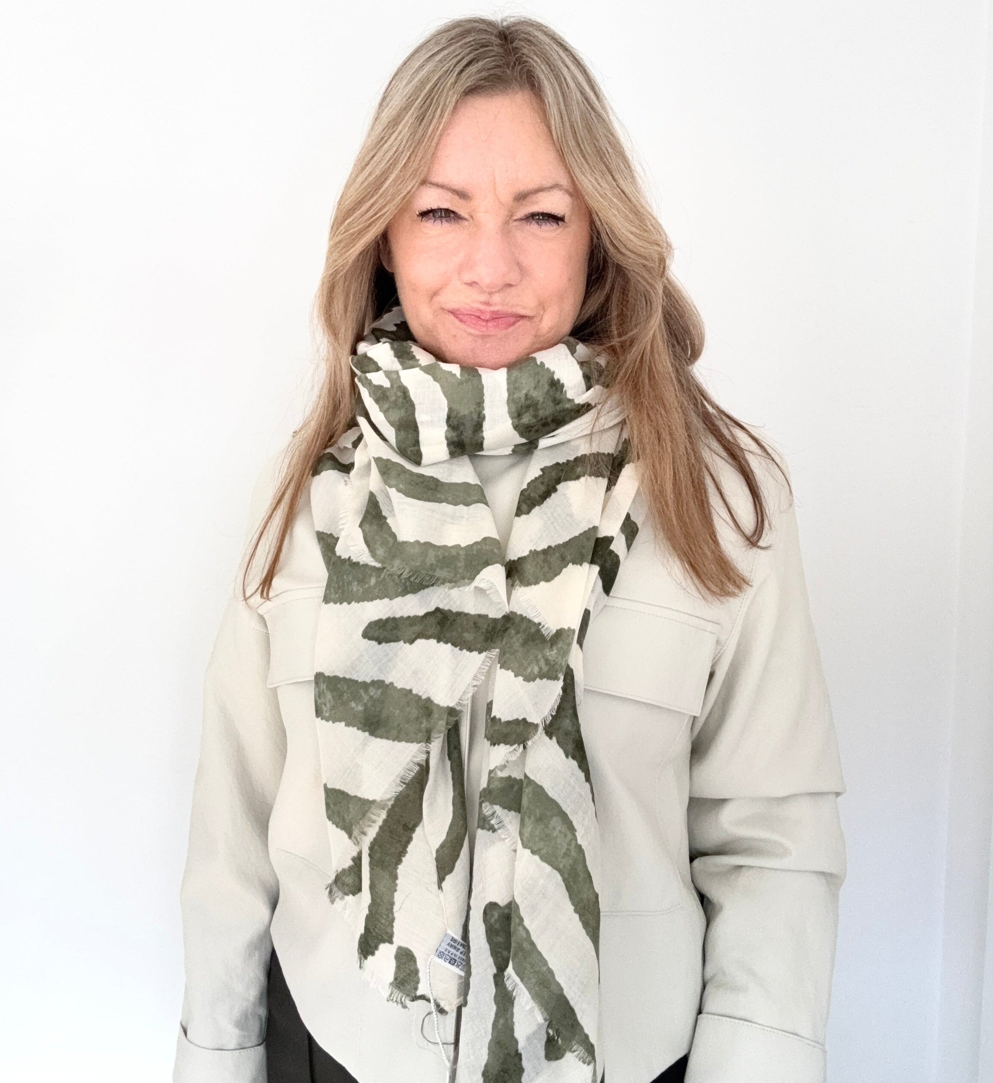 Woman wearing a white coat and khaki zebra print lightweight scarf 