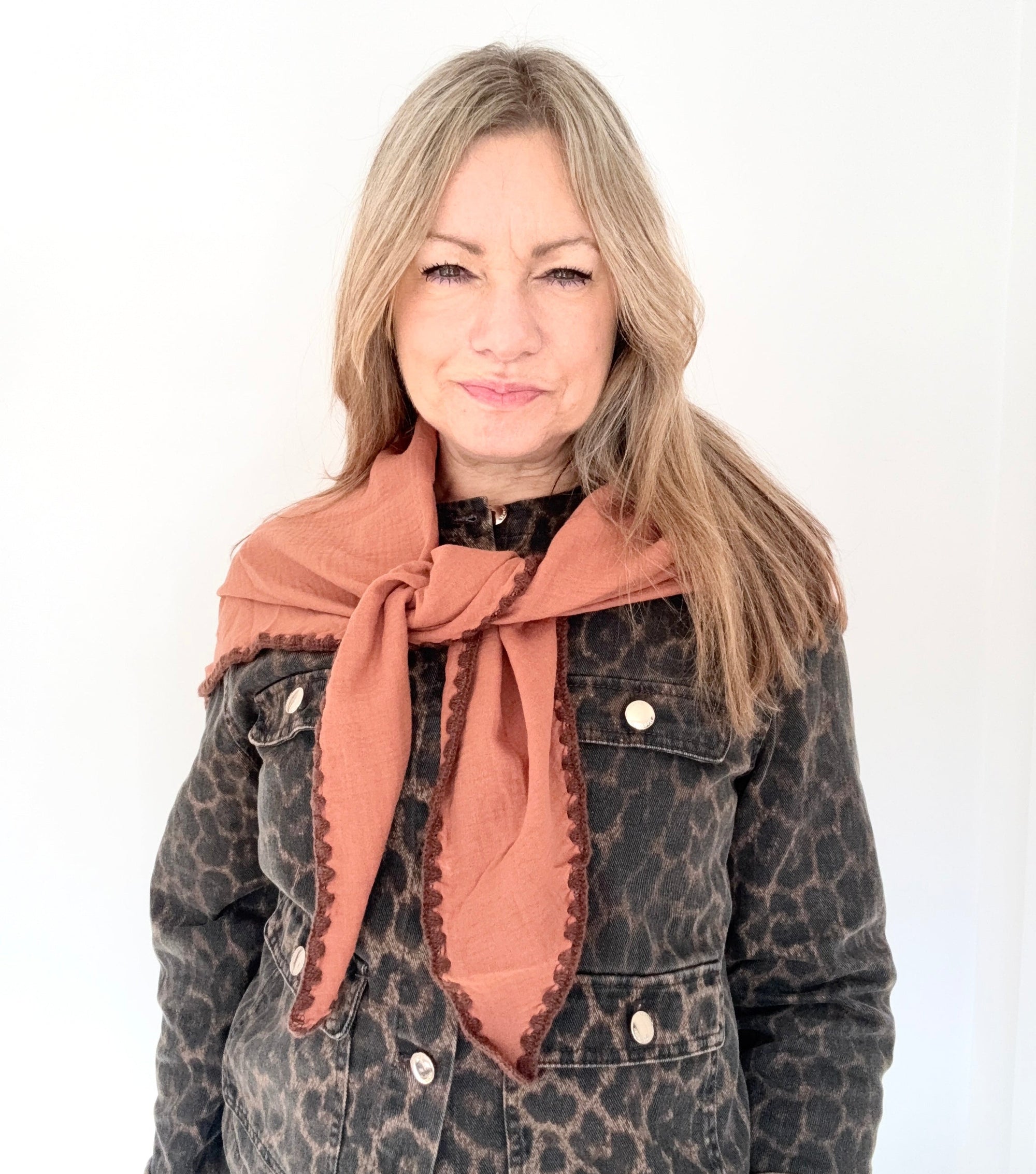 Woman wearing a leopard print jacket and a tan & brown triangle scarf 