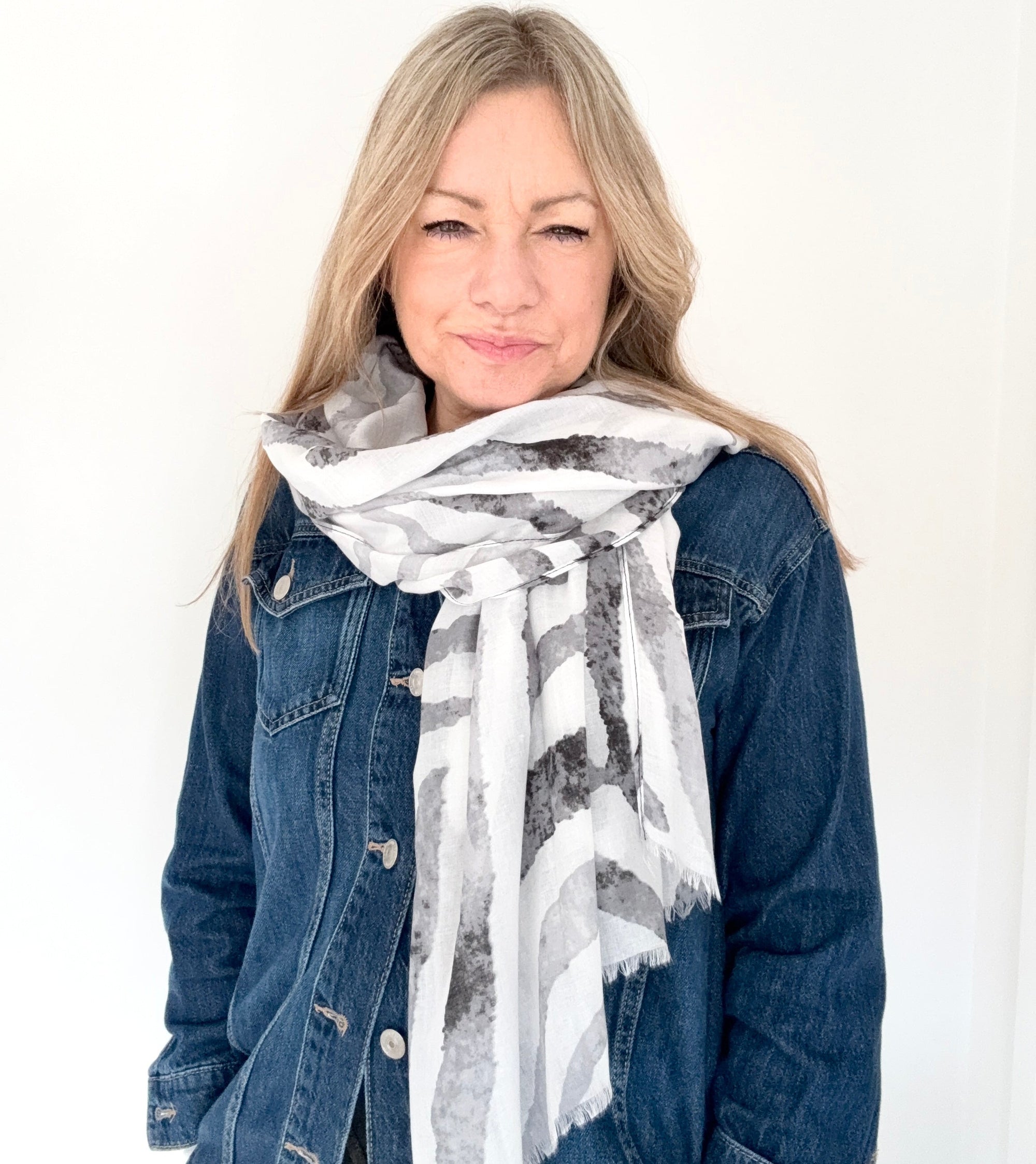 Woman wearing a grey zebra print scarf and denim jacket 