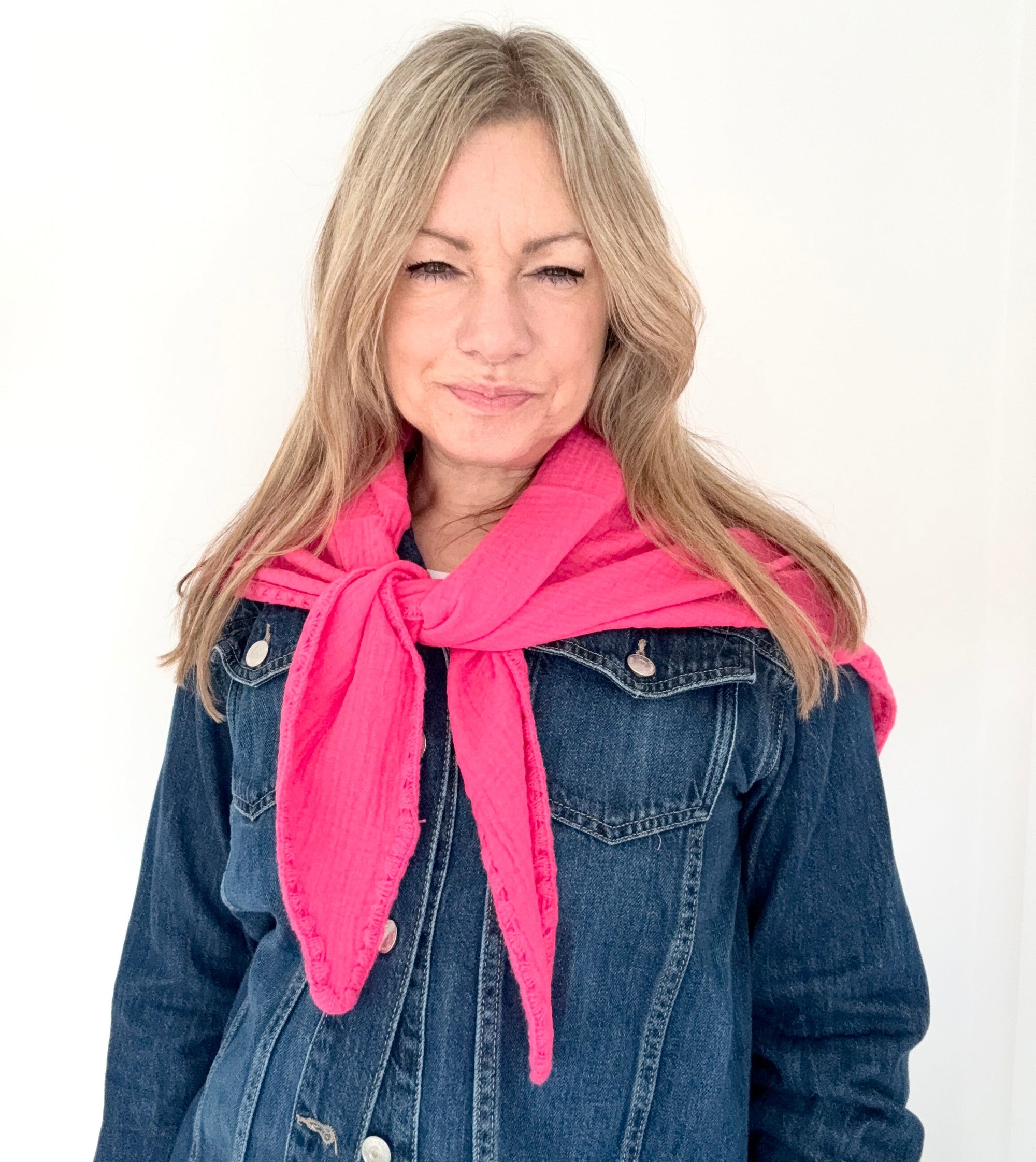 Woman wearing a pink cotton triangle scarf and blue denim jacket on a white background