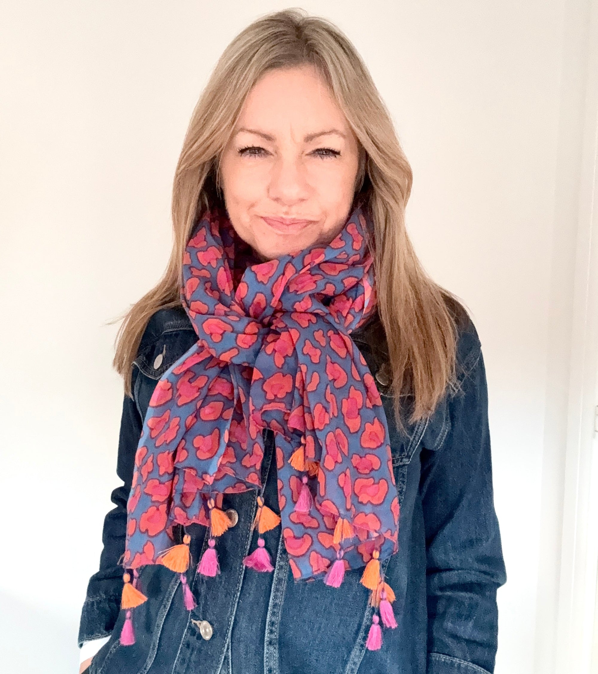 Woman wearing a blue, pink & orange animal print scarf with tassels