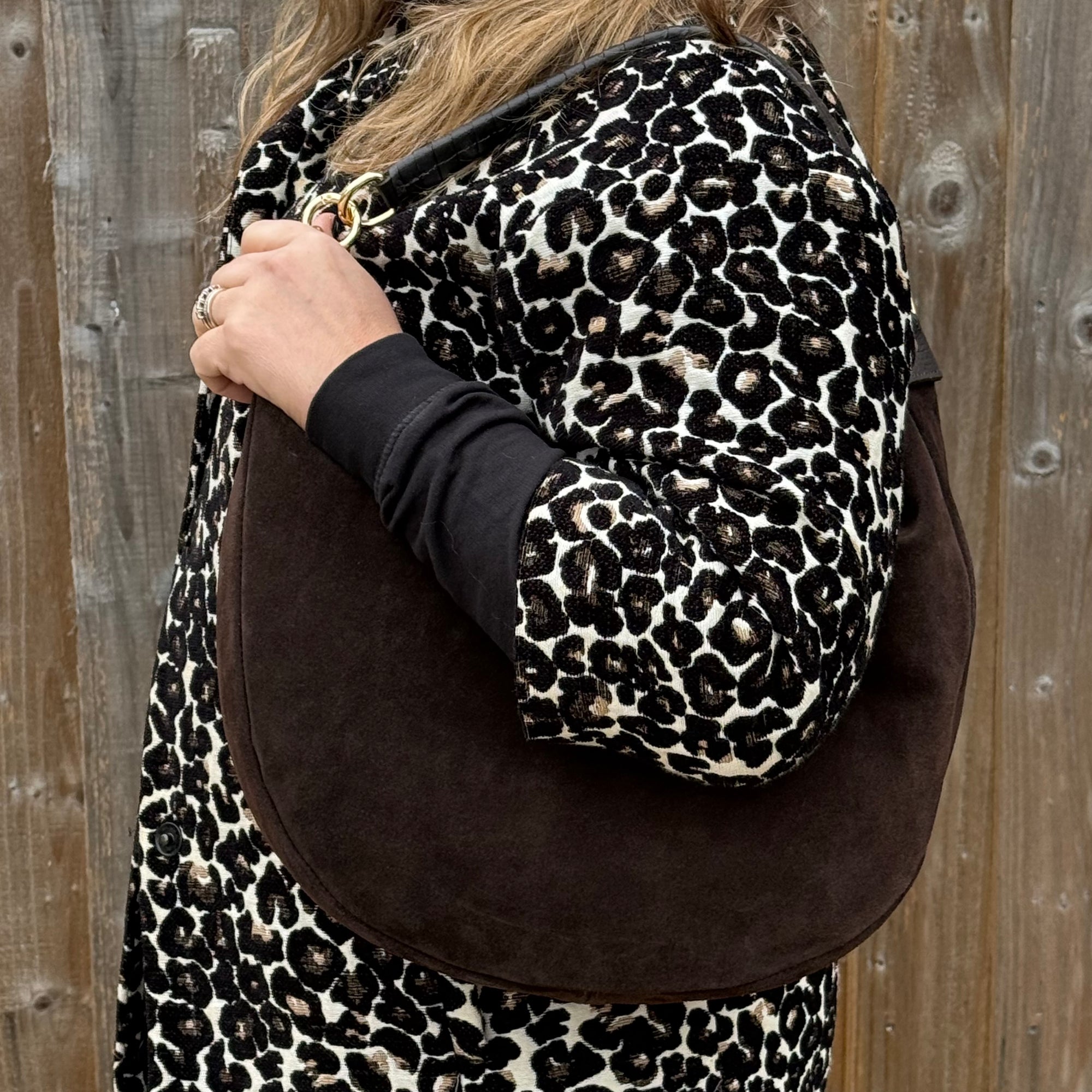Dark Brown Suede shoulder bag held by a woman in a leopard coat