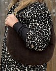 Dark Brown Suede shoulder bag held by a woman in a leopard coat