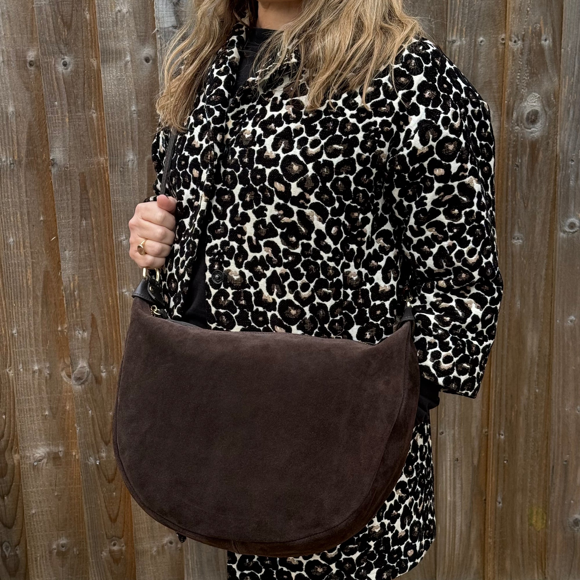 Person wearing a leopard print outfit with a chocolate brown suede crossbody bag 