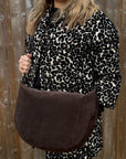 Person wearing a leopard print outfit with a chocolate brown suede crossbody bag 