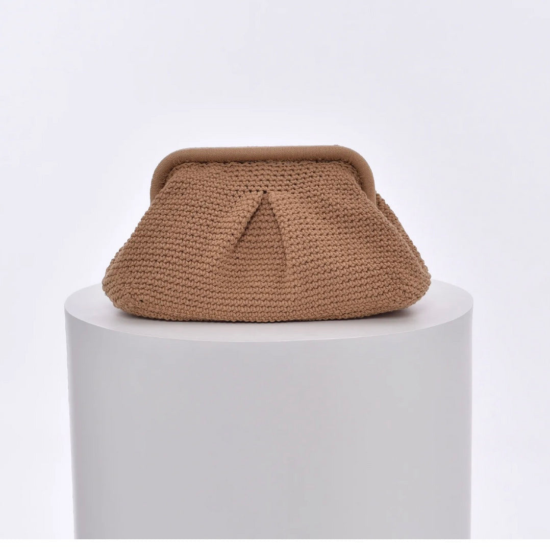 Beige knitted cloud clutch bag on a white pedestal with a light gray background