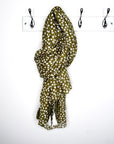 khaki and white polka dot scarf draped over a white wall with two hooks.