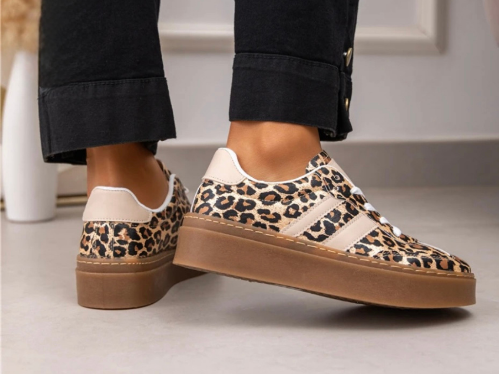 Leopard print sneakers with brown soles worn indoors on a light surface.