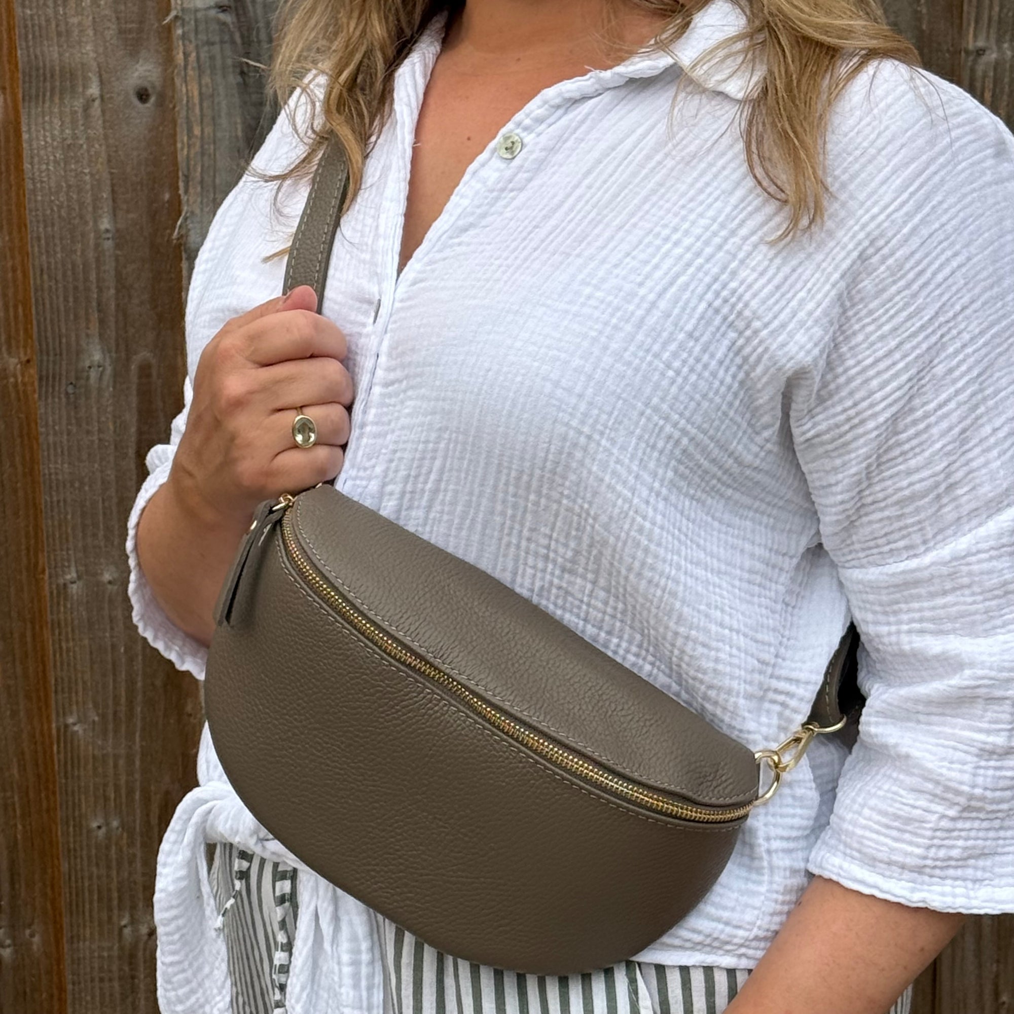 woman holding a large dark taupe leather crossbody bag 