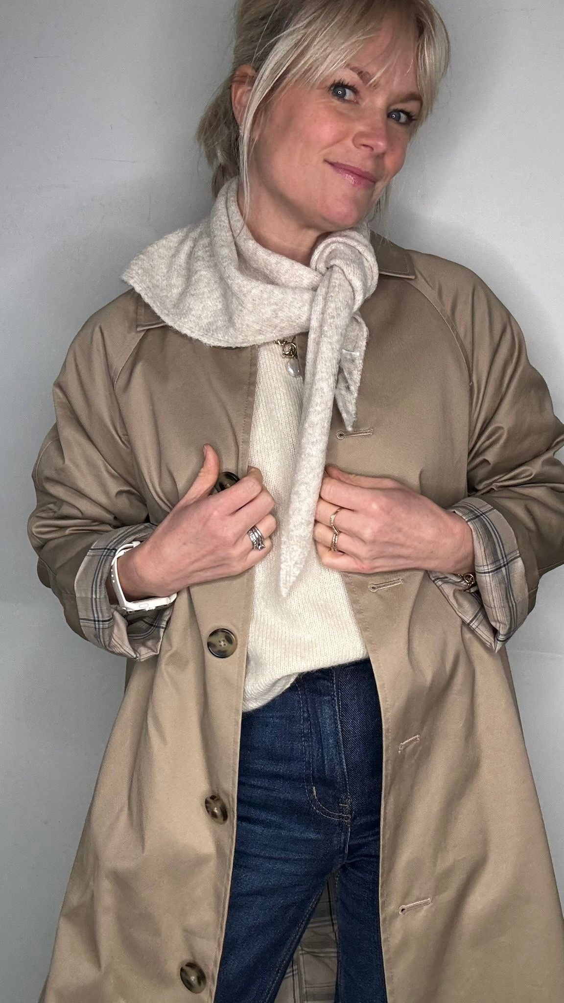 Woman wearing a beige trench coat and a light beige scarf
