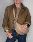 Woman wearing a brown jacket and holding a light taupe bag 