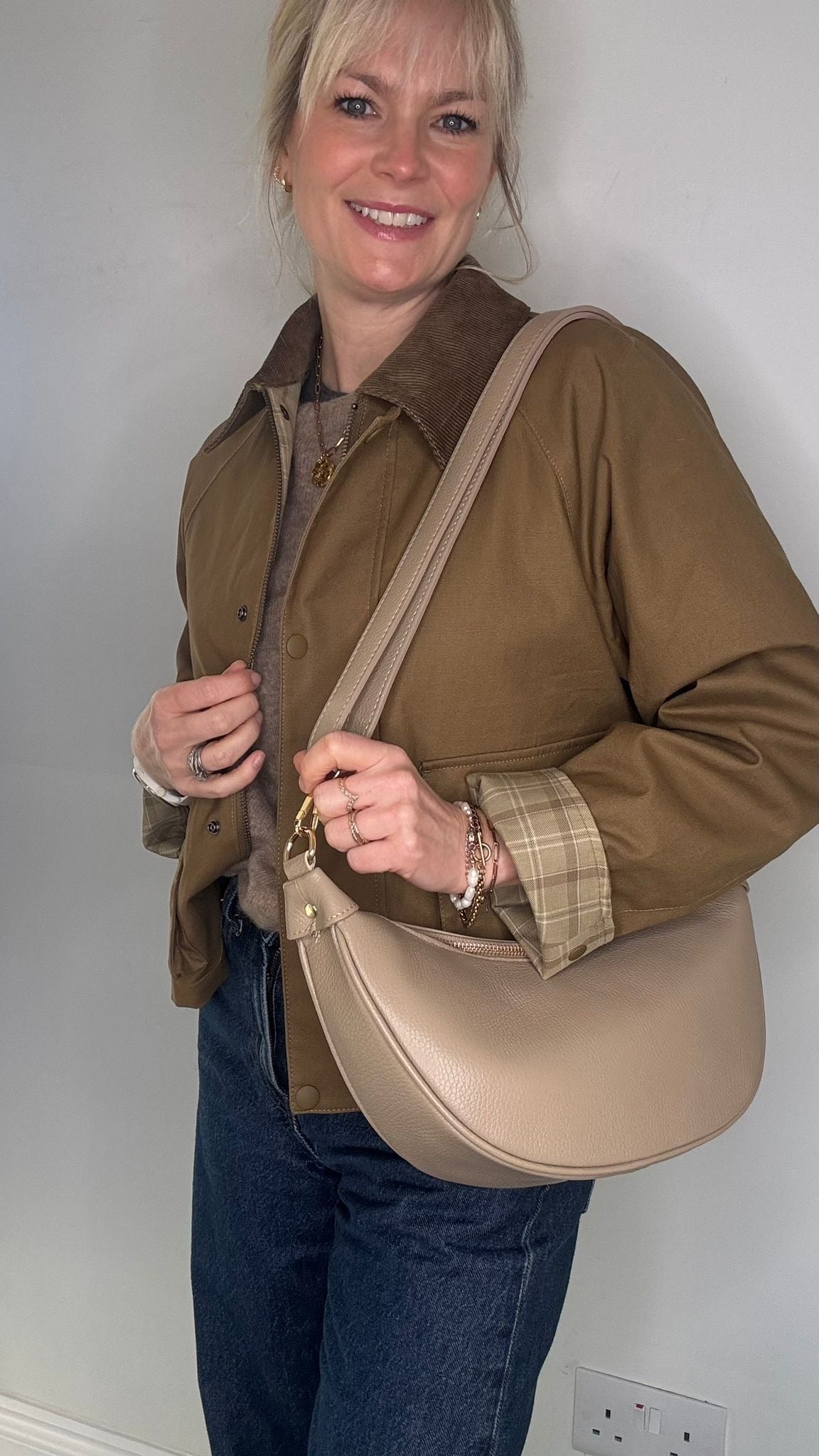 Woman holding a light taupe crossbody bag