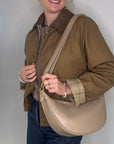 Woman holding a light taupe crossbody bag
