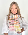 Woman wearing a colorful striped scarf against a white background.