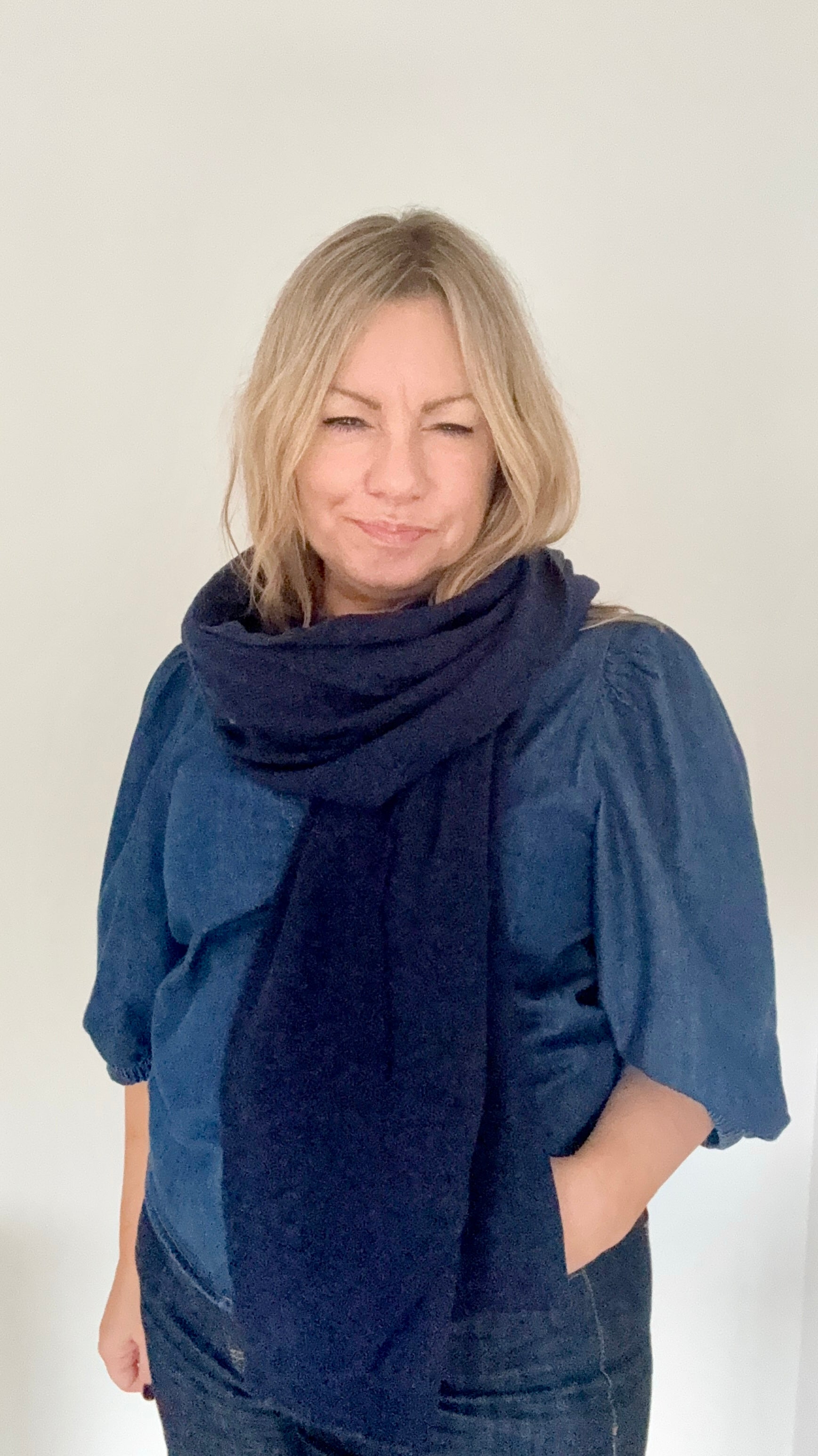 Woman wearing a large navy blue scarf 
over a blue denim top