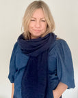 Woman wearing a large navy blue scarf 
over a blue denim top