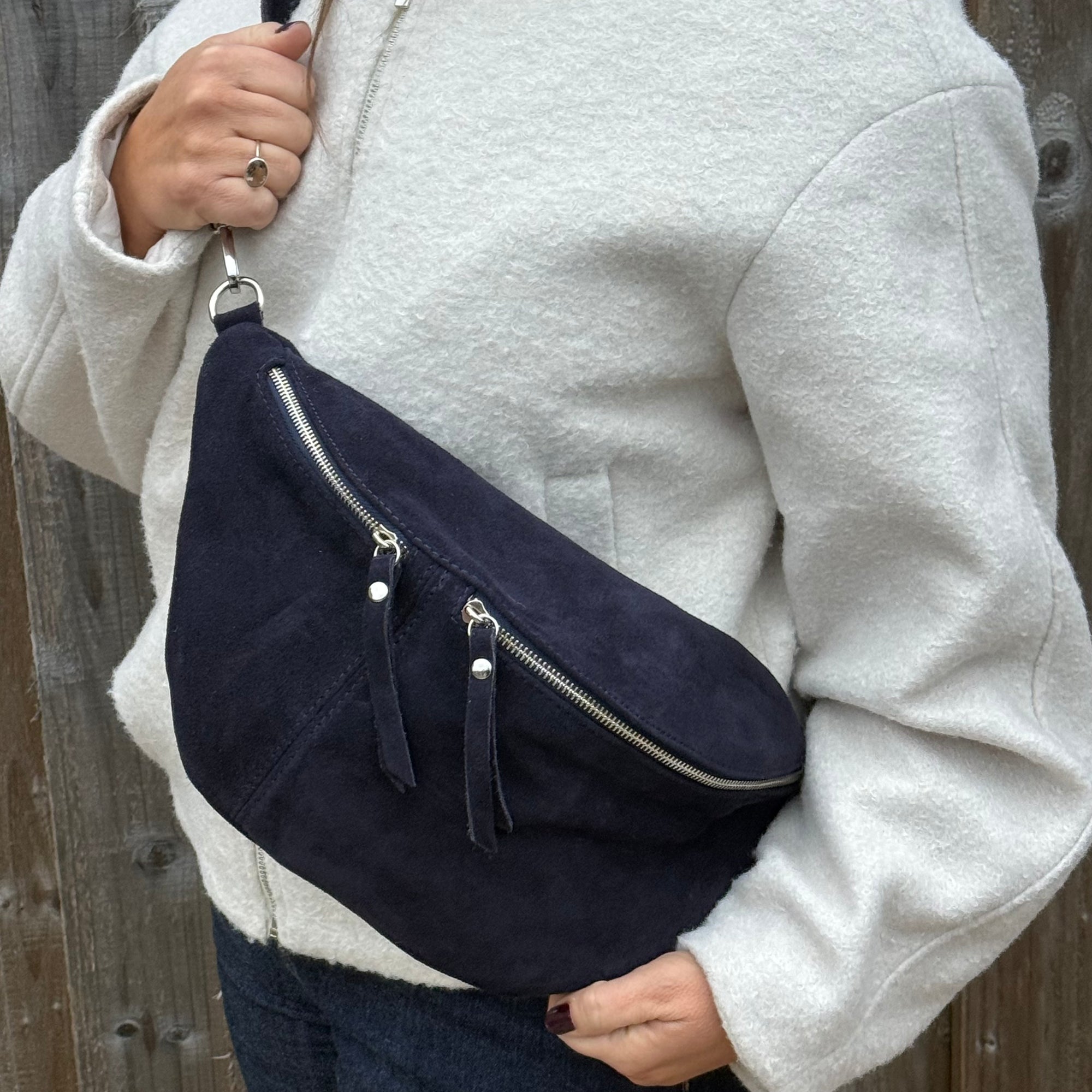 woman wearing a navy blue crossbody bum bag with silver accented zippers 
