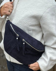 woman wearing a navy blue crossbody bum bag with silver accented zippers 
